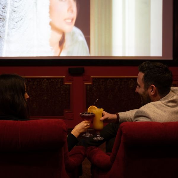 Couple Sitting in Abbey Movie Theatre with cocktails watching a movie